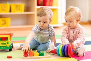 Preschool boy and girl playing on floor with educational toys. Children toddlers at home or daycare.